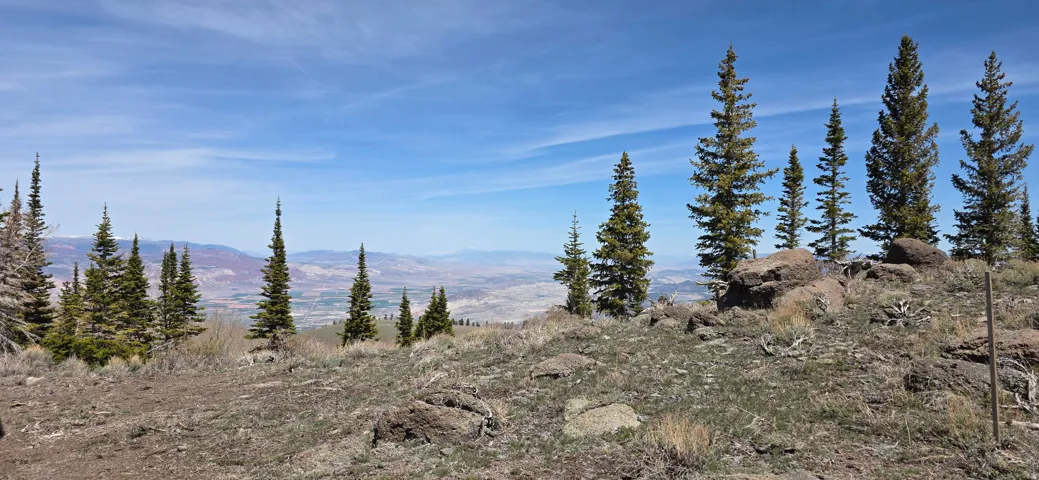 Expansive high-altitude landscape with distant valley and mountain ranges