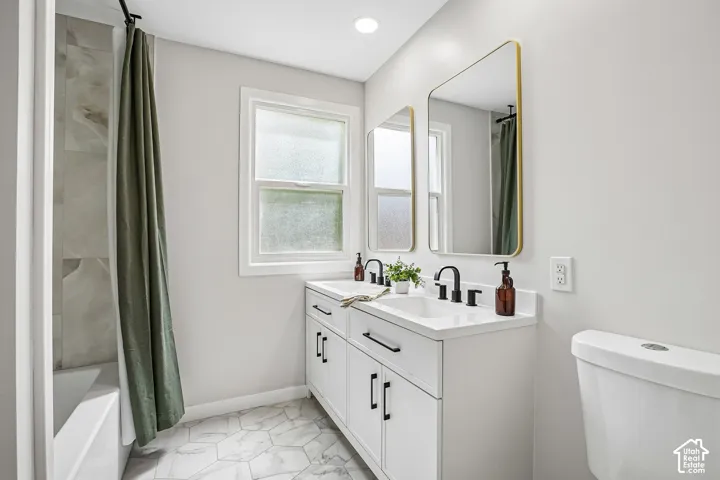 Dual vanity featuring white cabinetry, black hardware, and two gold-framed mirrors