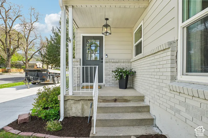 Inviting front entry featuring a covered porch, concrete steps, and white metal railings