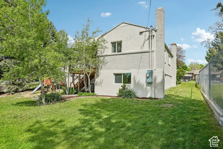Expansive lawn area presenting the property's exterior, featuring a brick chimney and a wood-frame deck