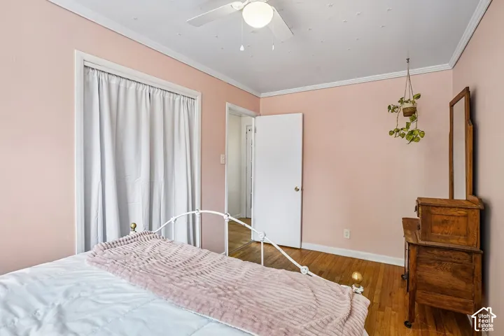 Room featuring hardwood flooring, light pink wall paint, white trim, and a ceiling fan with integrated lighting