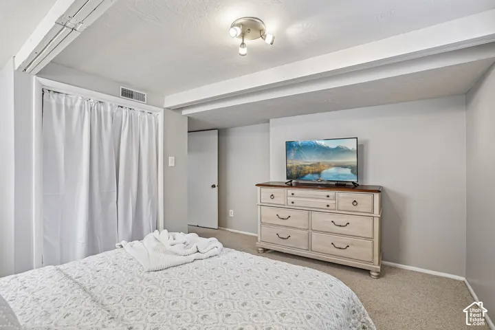 Recessed ceiling beams, neutral carpeting, and light gray wall paint create a bright interior