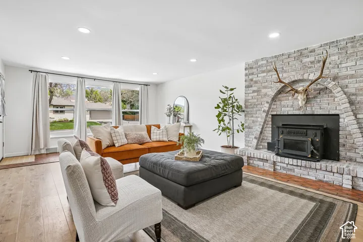 Living area featuring light wood-finish flooring, recessed lighting, and a brick fireplace with a wood-burning insert