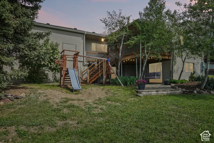 Expansive backyard featuring a multi-level deck, string lighting, and mature trees