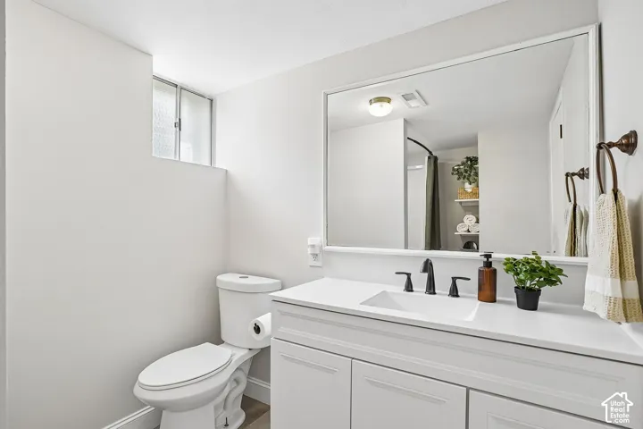 Bathroom vanity featuring a single basin, solid surface countertop, matte black faucet, and white cabinetry