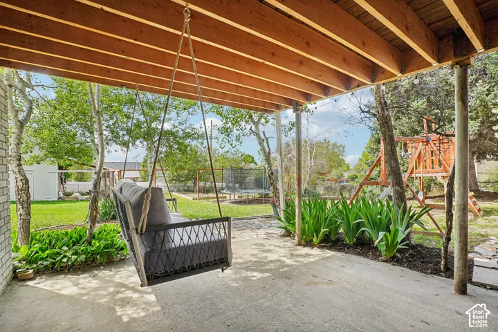 Covered patio area featuring a concrete surface and exposed wood beam ceiling