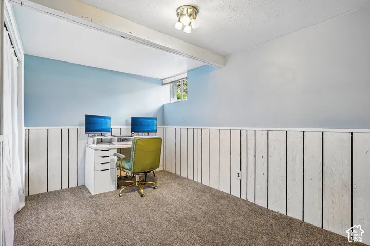 Carpeted room featuring light blue walls above white wood paneling