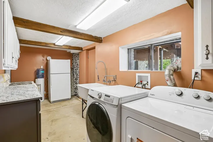 Laundry area featuring a utility sink with a high-arc faucet, a window, and exposed wood beams