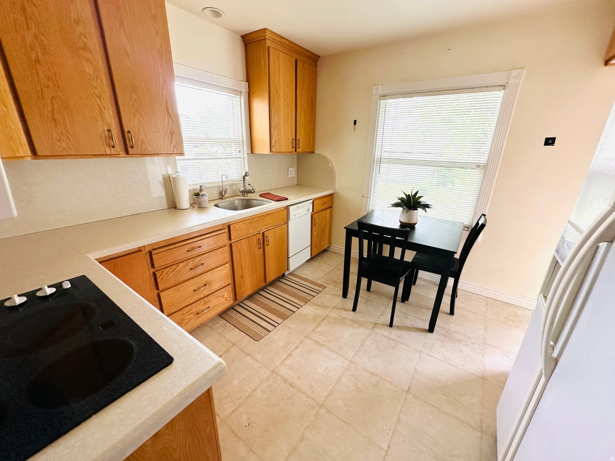 Kitchen featuring wood cabinetry, light countertops, a built-in cooktop, a stainless steel sink, and tile flooring