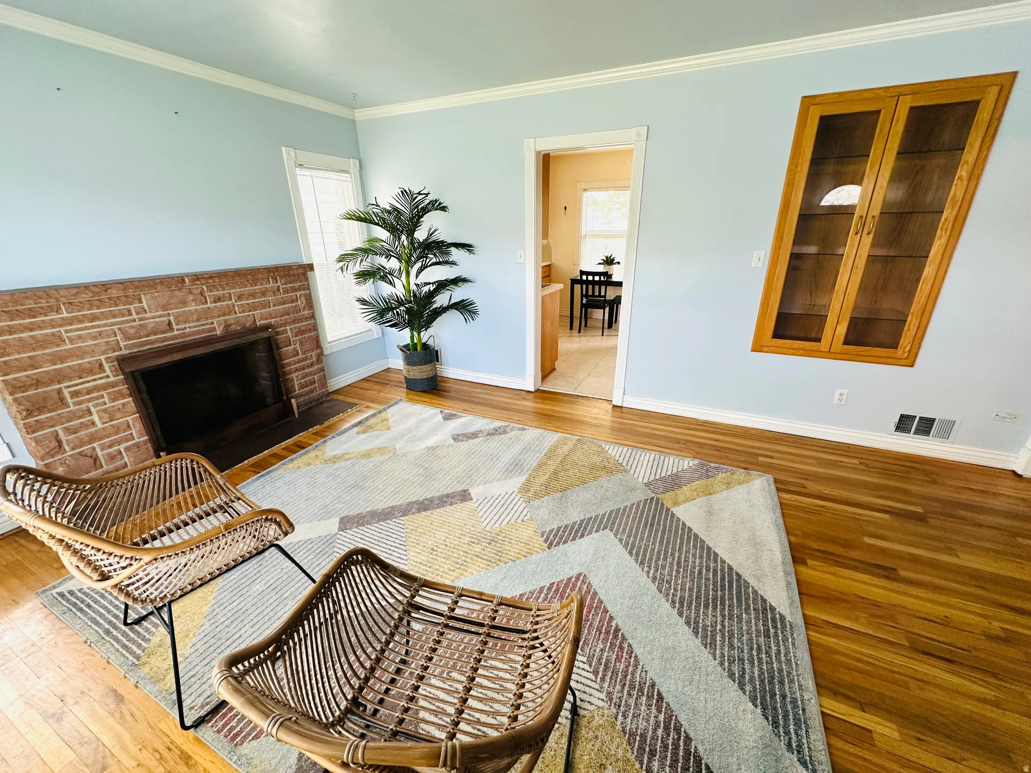 Living area featuring wood-finish flooring, a stone fireplace, and light-toned walls with white trim
