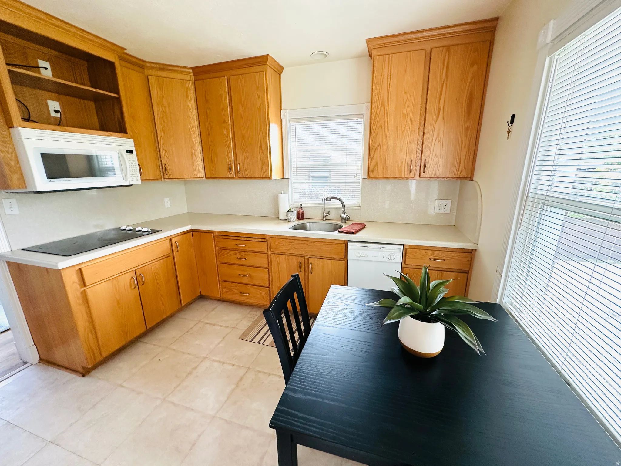 Kitchen featuring wood cabinetry, light-toned countertops, a built-in microwave, and a glass cooktop
