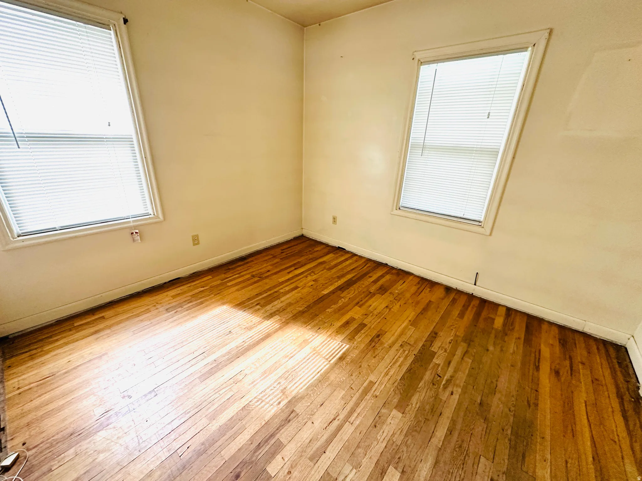 Wood-finish flooring throughout this room with dual windows featuring blinds