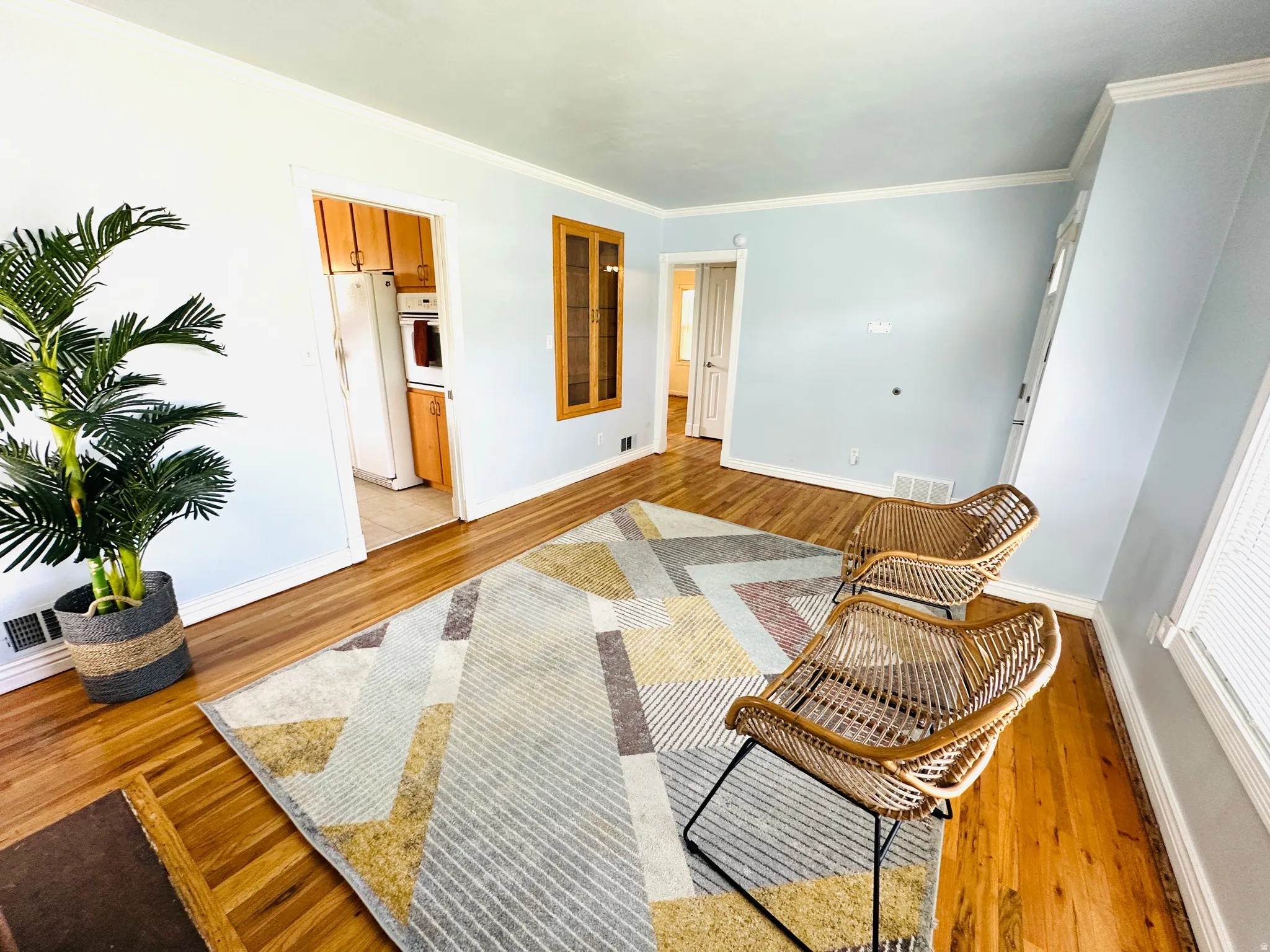 Hardwood flooring extends throughout this space, complemented by light blue walls and white crown molding