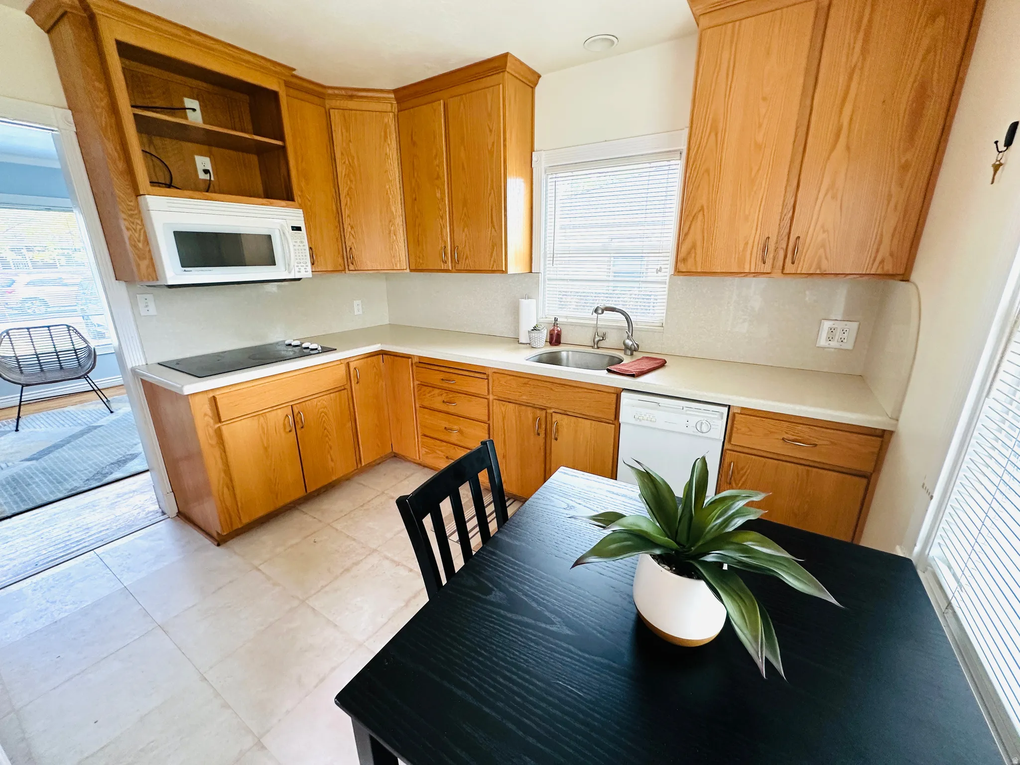 Kitchen featuring wood cabinetry, light-toned countertops, a stainless steel sink, tile flooring, and a built-in microwave