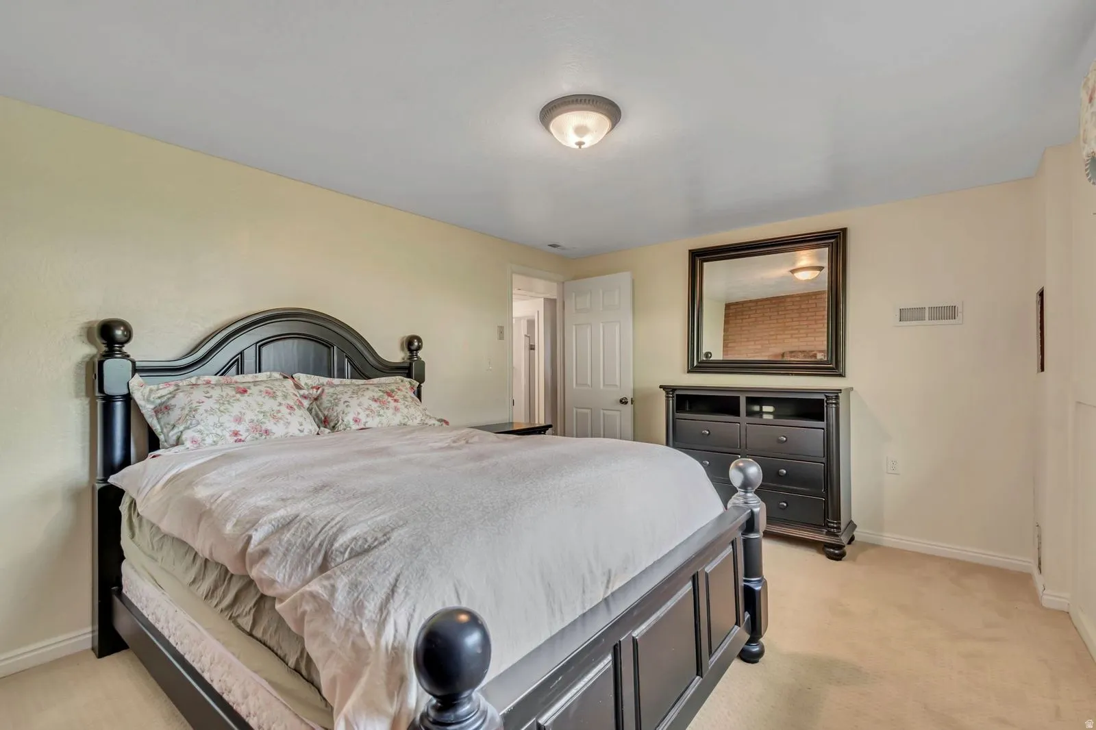 Bedroom featuring neutral-toned walls, carpet flooring, a white interior door, and a flush-mount ceiling light fixture