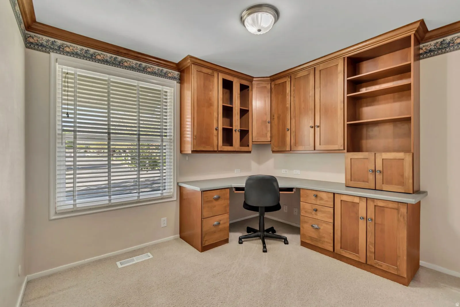 Built-in wood cabinetry with integrated desk space and shelving, featuring light-toned countertops and under-cabinet lighting