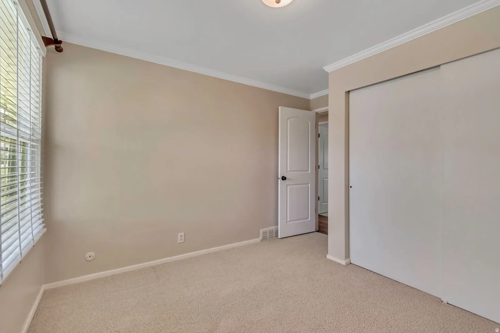 Neutral-toned interior with light carpet flooring, crown molding, and white trim
