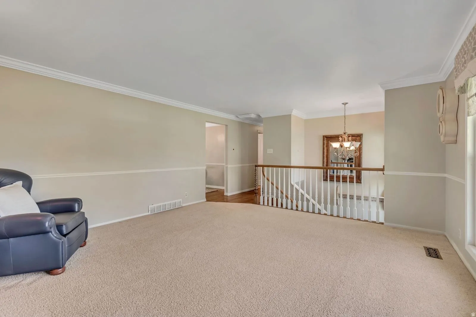 Spacious room featuring neutral carpeting, two-tone painted walls, and white crown molding