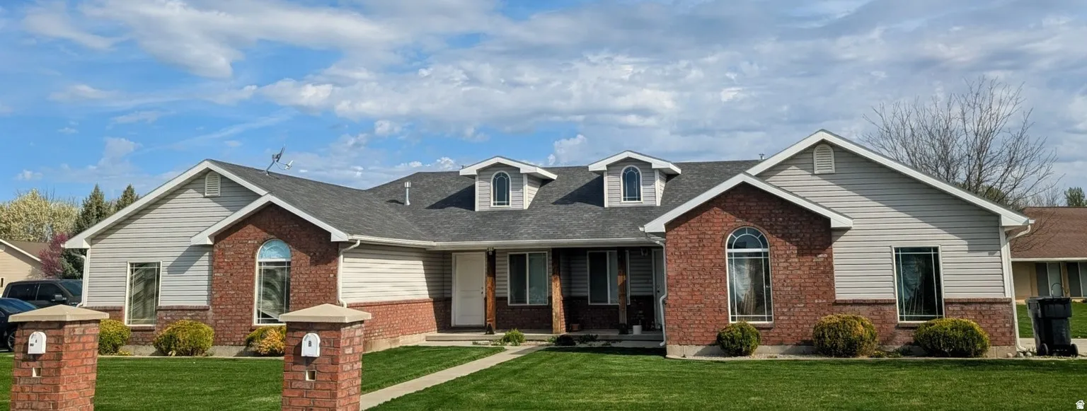 Brick and siding exterior featuring multiple dormer windows and an arched entryway
