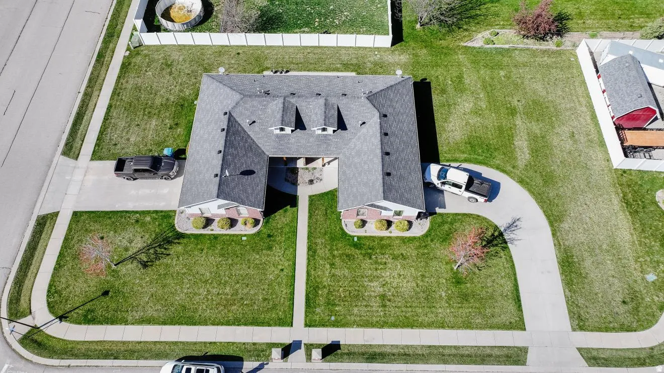 U-shaped residence featuring a dark shingle roof and brick facade accents