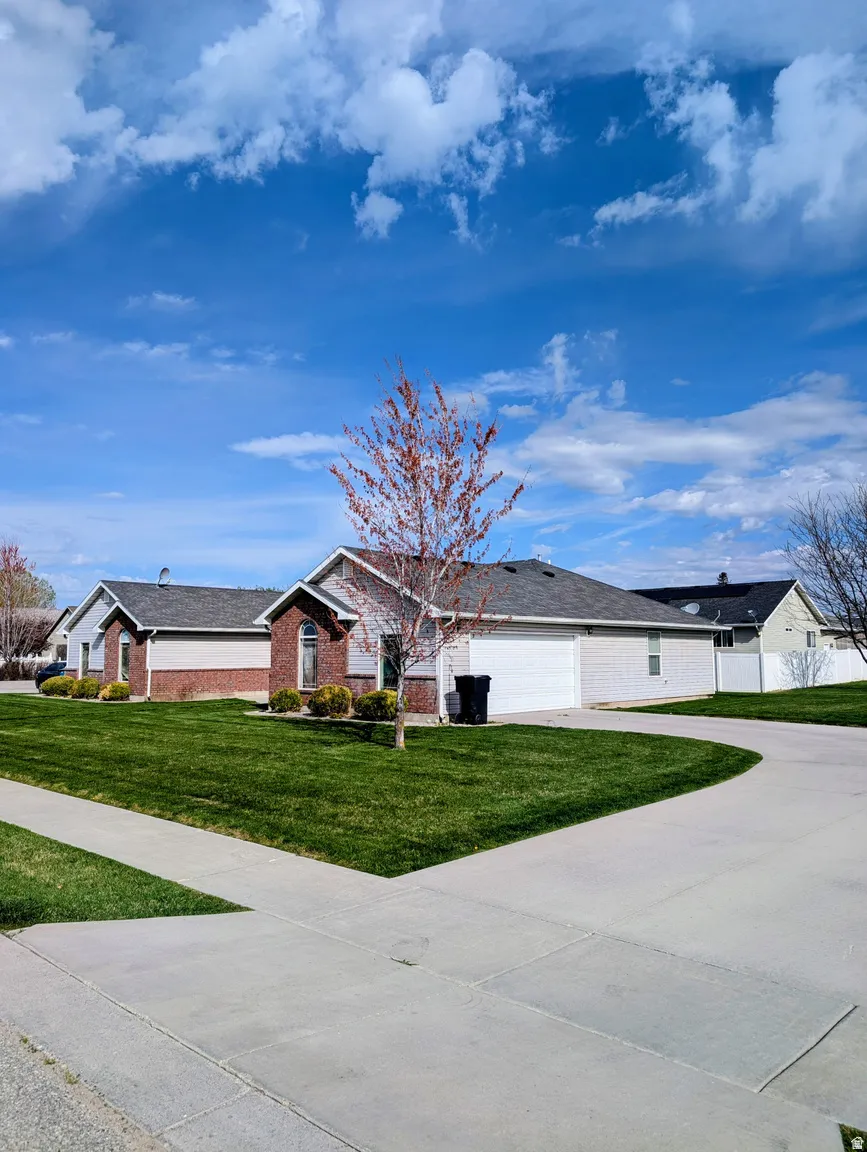 Ranch-style exterior with brick and siding accents, featuring a two-car garage, concrete driveway, and a front yard with established landscaping