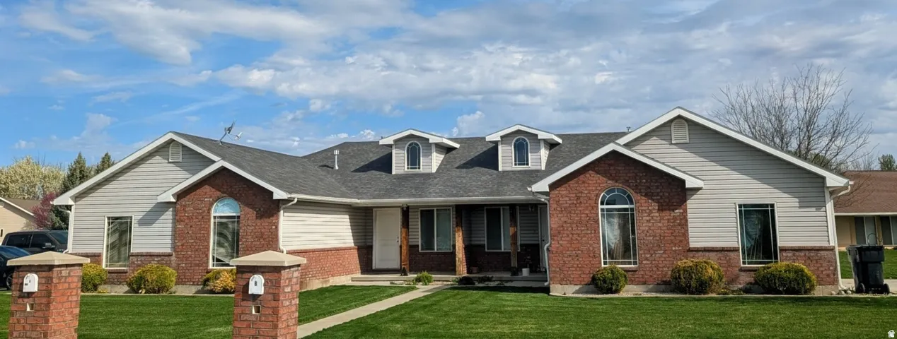Brick and siding exterior featuring multiple dormer windows and an arched entryway