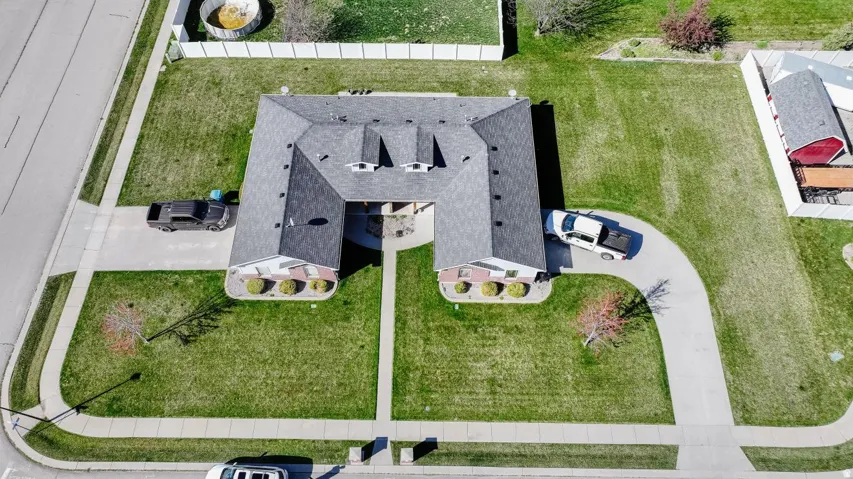 U-shaped residence featuring a dark shingle roof and brick facade accents