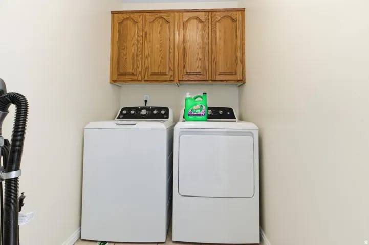 Dedicated laundry space featuring upper wood cabinetry and light-toned walls