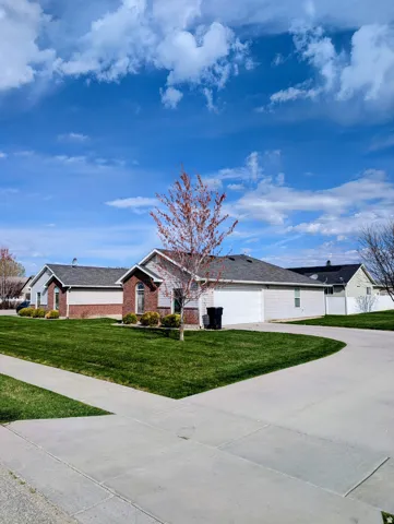 Ranch-style exterior with brick and siding accents, featuring a two-car garage, concrete driveway, and a front yard with established landscaping