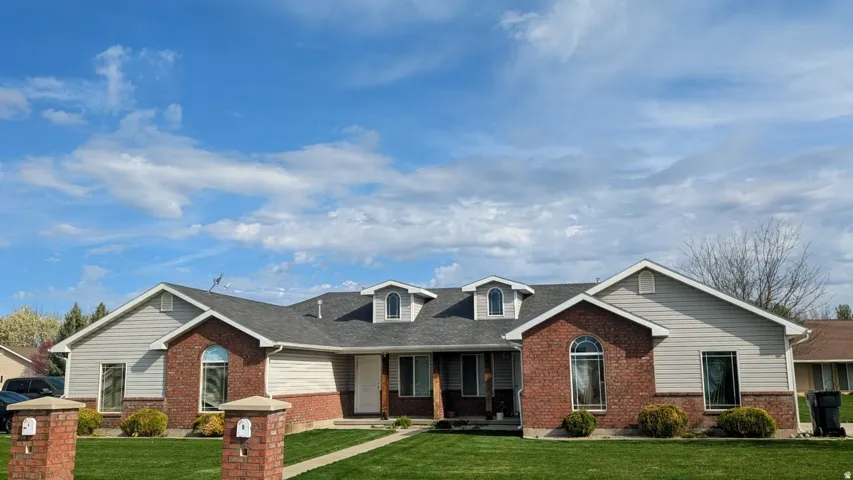 Expansive brick and siding exterior featuring a grey shingle roof and multiple dormer windows