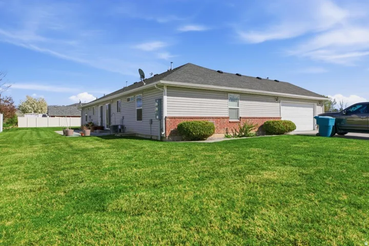 Expansive green lawn surrounds this property featuring light-colored siding and a brick-clad foundation