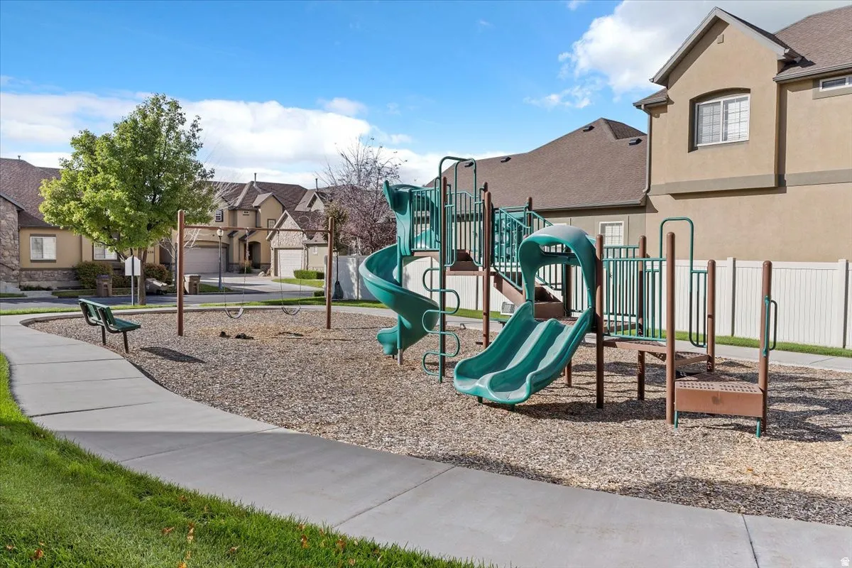 Community playground featuring a multi-level play structure with slides, swings, and a wood chip surface