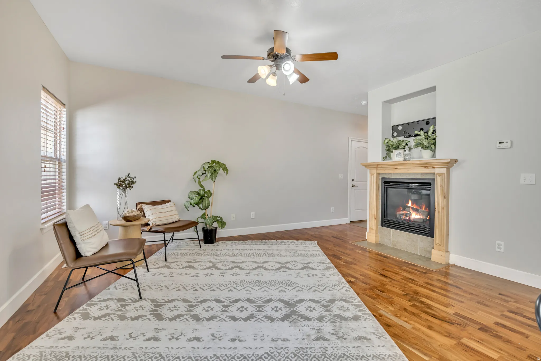 Living area featuring wood-finish flooring, a light-toned ceiling, and a ceiling fan with integrated lighting