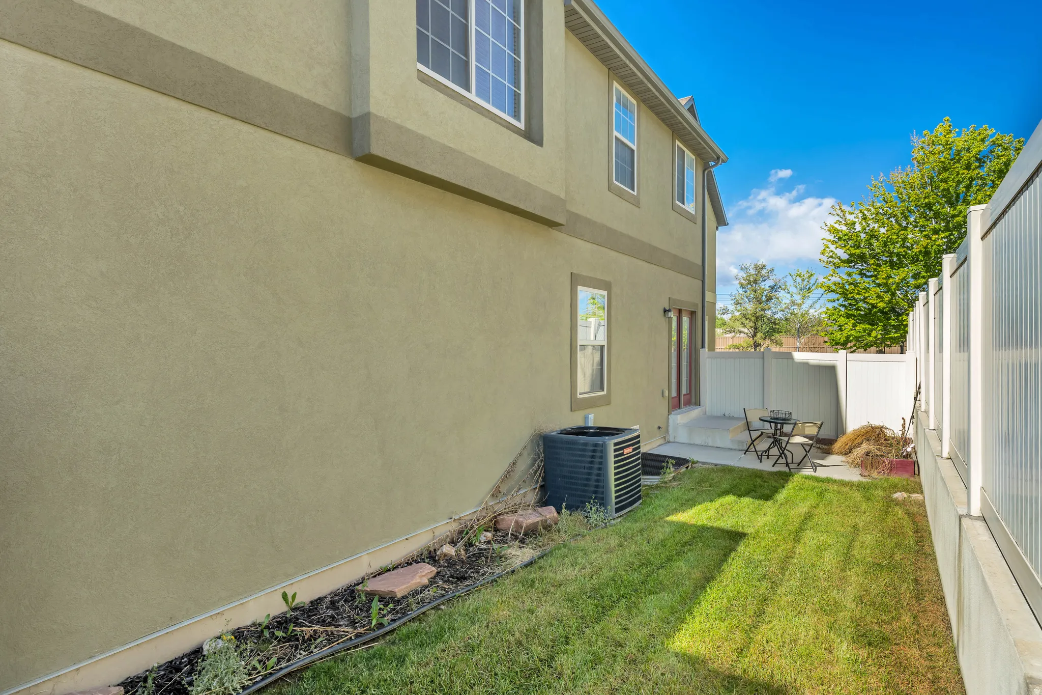 Private backyard featuring a concrete patio, a manicured lawn, and a white privacy fence