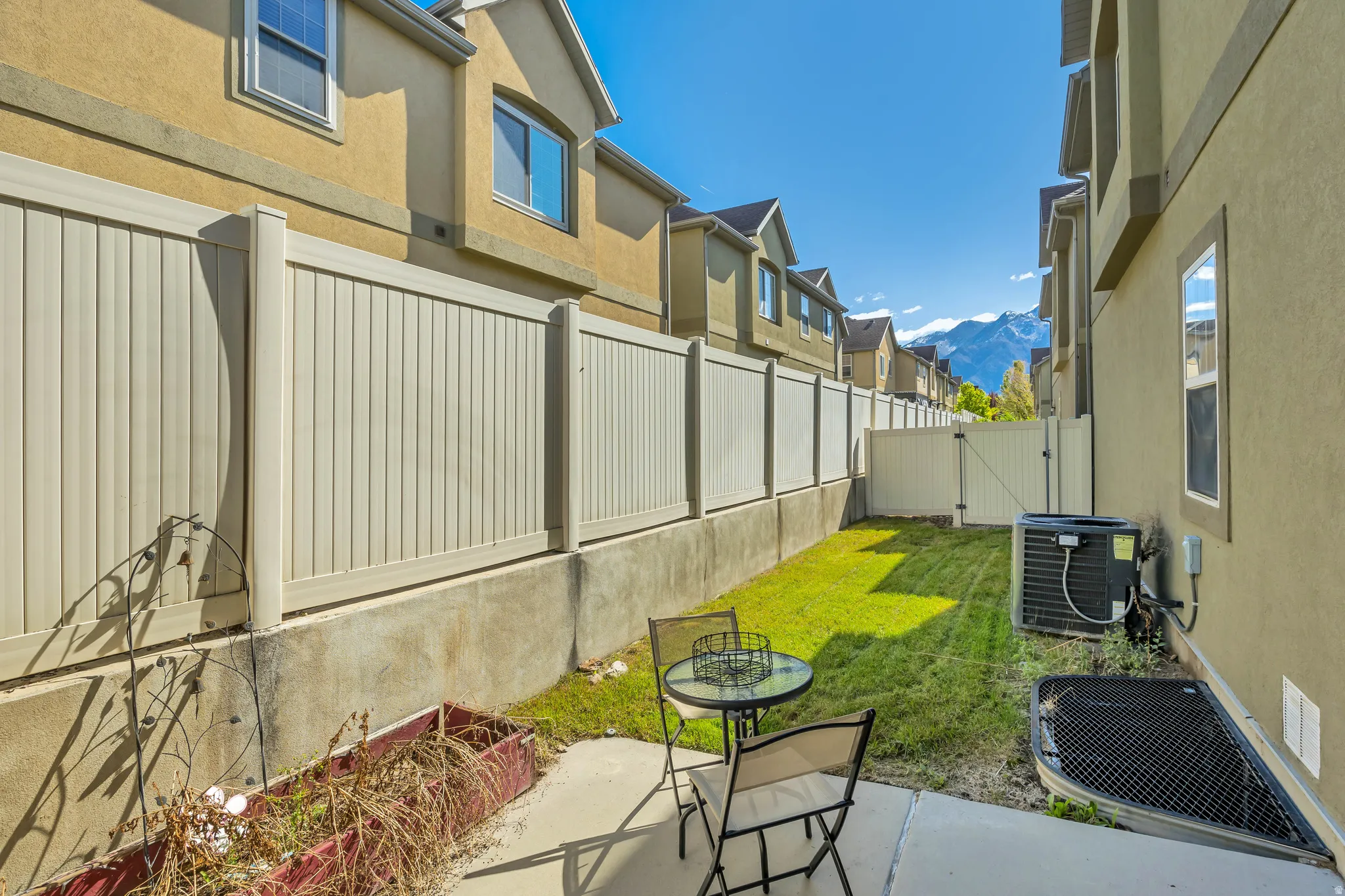 Rear yard featuring a concrete patio, a strip of grass, and tall privacy fencing
