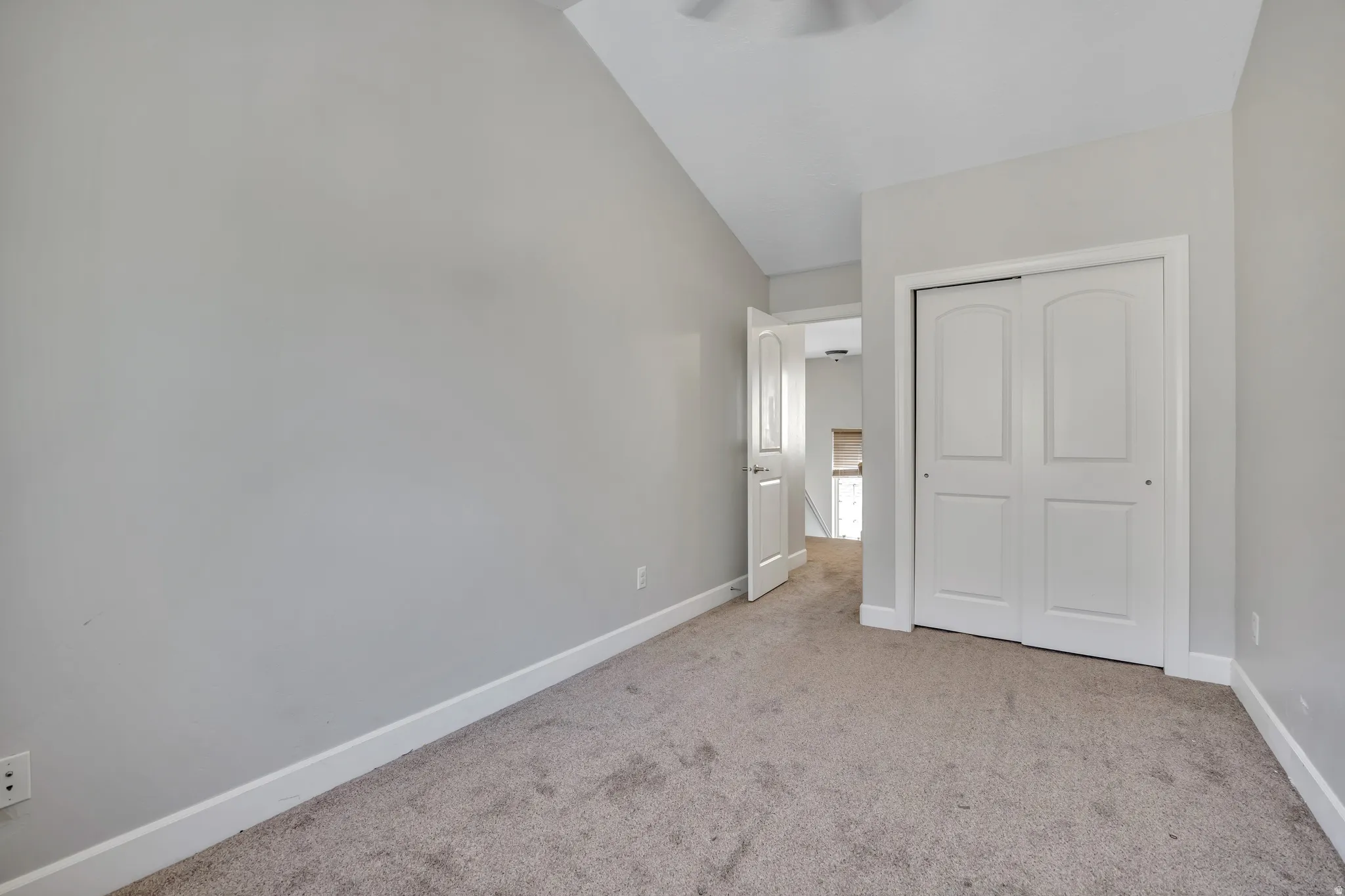 Carpeted room featuring light gray walls, white baseboards, and a white bi-fold closet door