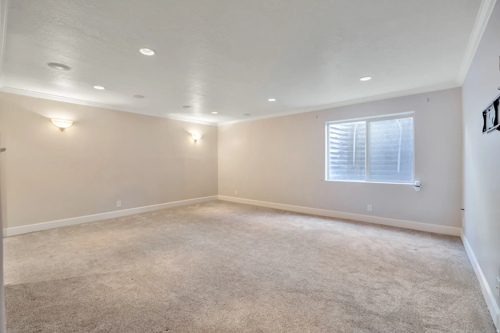 Spacious room featuring neutral carpeting, light-toned walls, recessed lighting, and crown molding