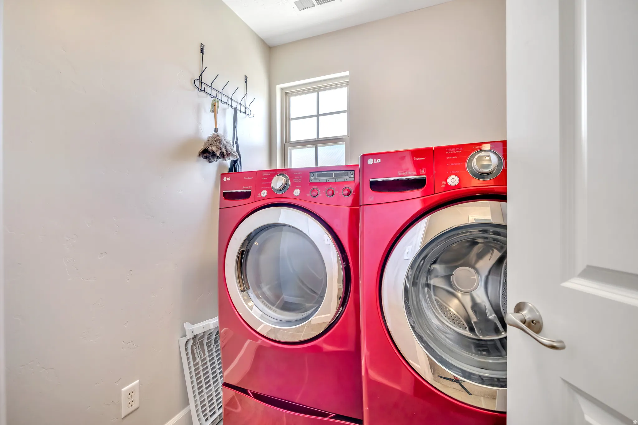 Dedicated laundry area with a window providing natural light and a wall-mounted rack for hanging items