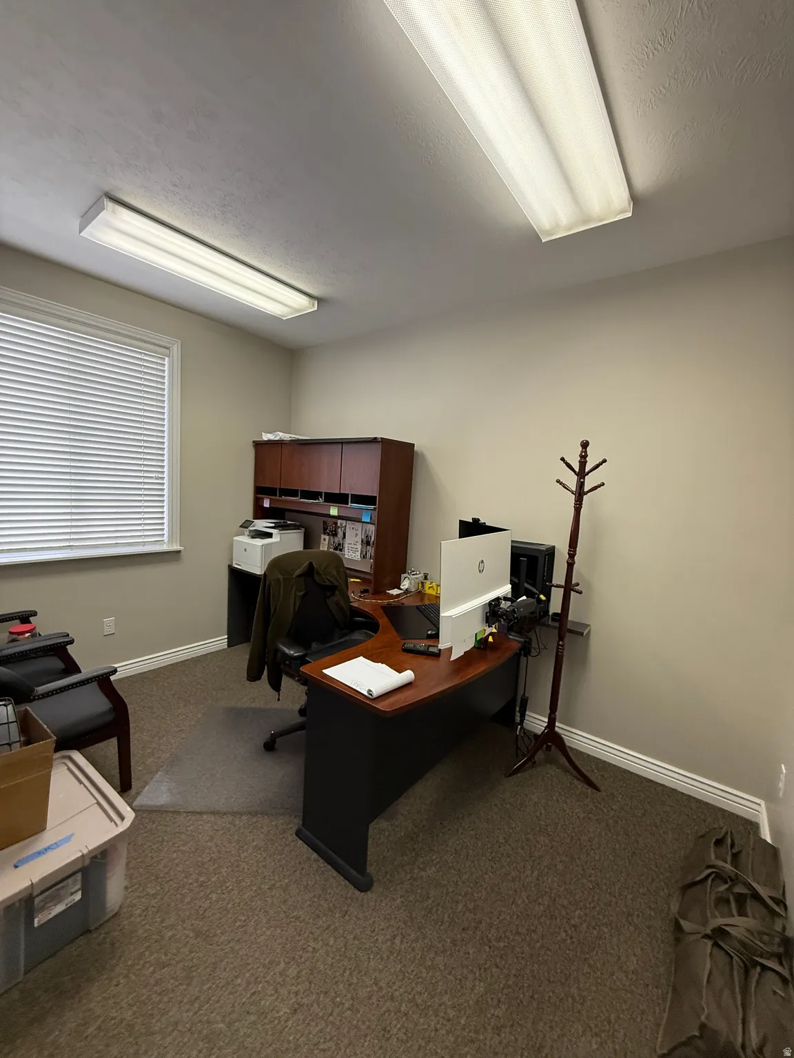 Commercial office space featuring neutral-toned walls, textured carpeting, and white baseboards
