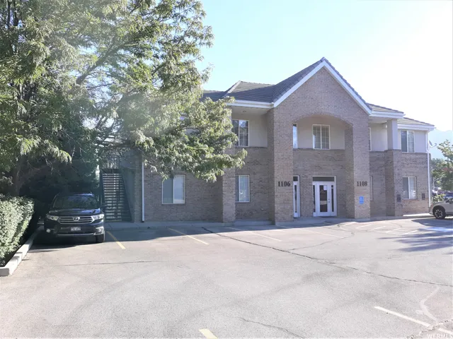 Multi-unit building featuring a brick facade with light-toned stucco accents and a prominent arched entry