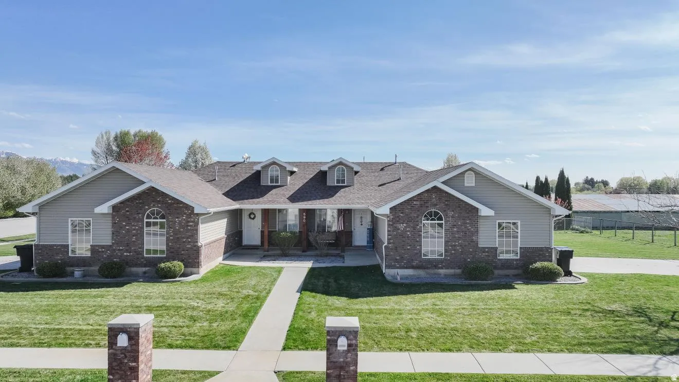 Duplex property featuring a brick and siding exterior, arched windows, and a manicured lawn