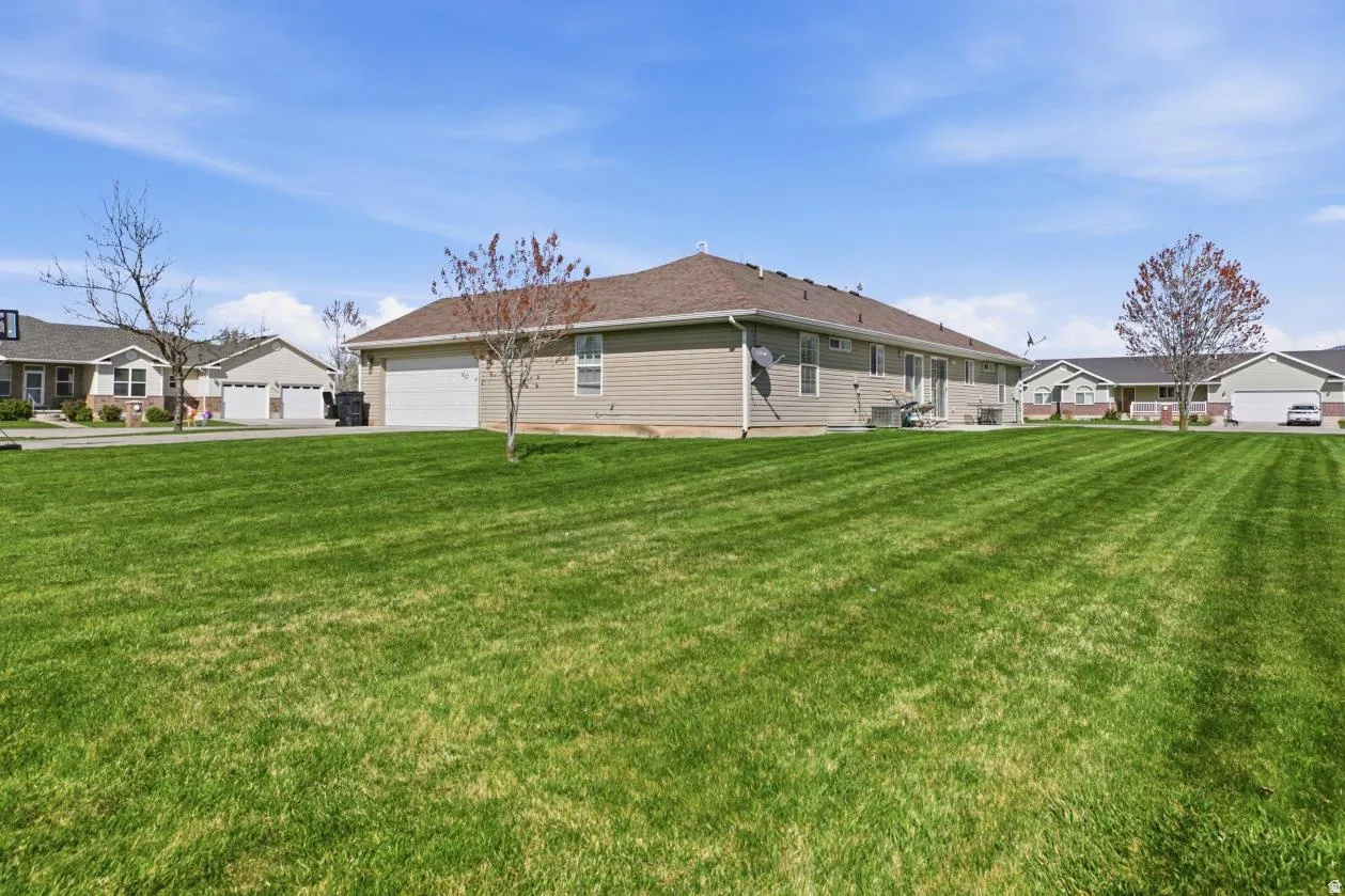 Expansive green lawn with a visible side exterior featuring horizontal siding and a shingled roof