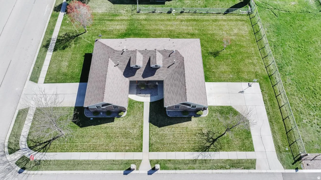U-shaped building with a brown shingle roof, surrounded by green lawns