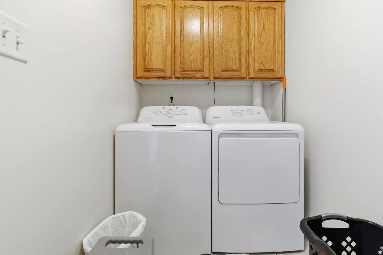 Laundry area featuring built-in wood cabinetry, overhead storage, and white walls