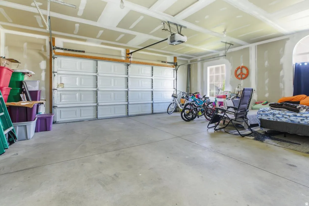 Spacious garage featuring two overhead doors, a transom window, concrete flooring, and an arched wall opening