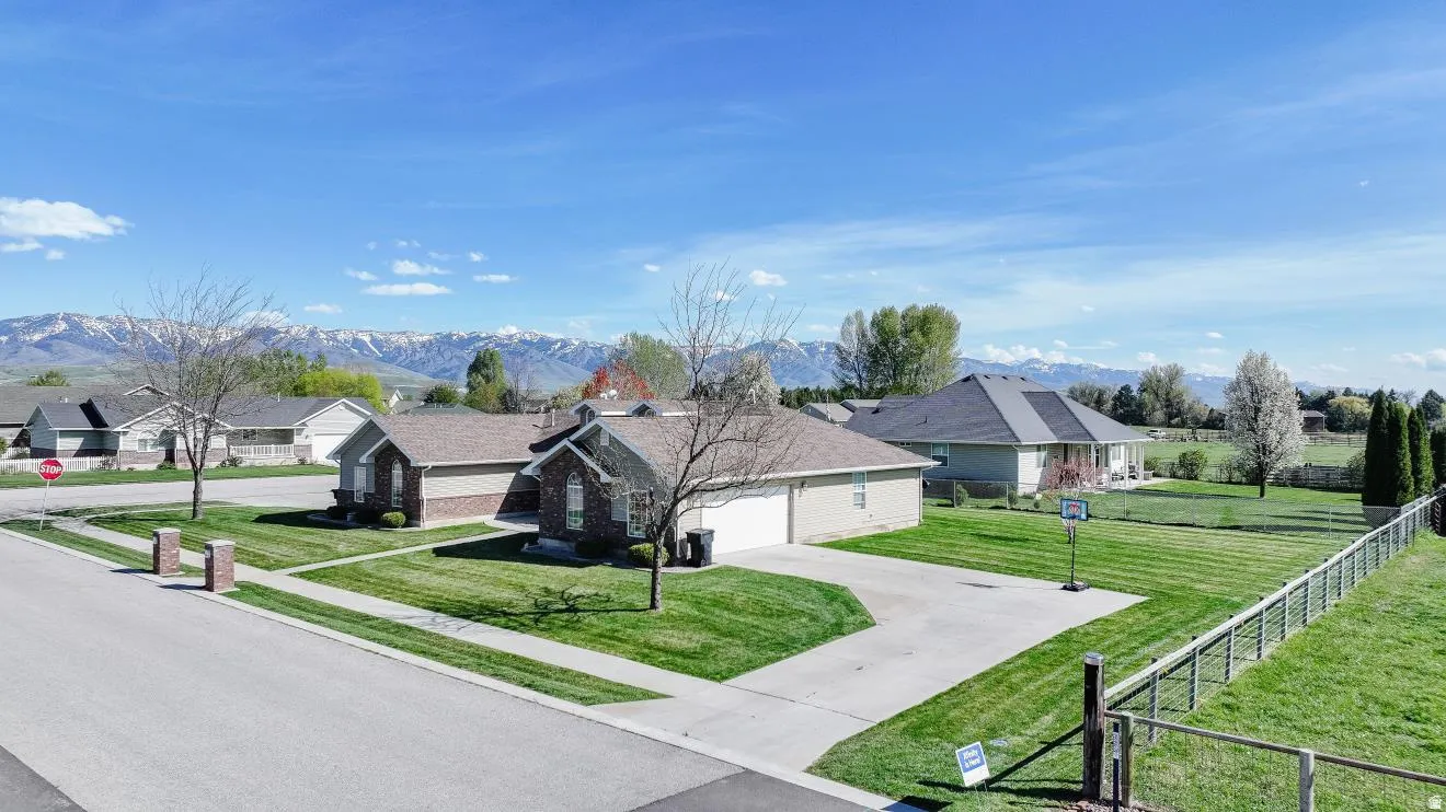 Expansive residential property featuring a large green lawn, a light-colored exterior, and a paved driveway