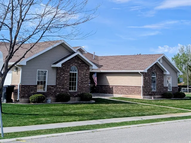 Ranch-style exterior featuring a combination of brick and siding, multiple gabled rooflines, arched window accents, and a sidewalk border