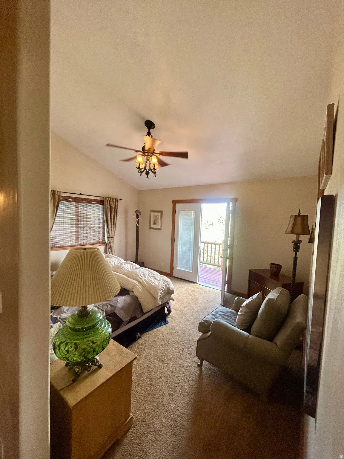 Primary Bedroom with vaulted ceilings and warm carpeting define this room, featuring a private exterior door leading to a deck