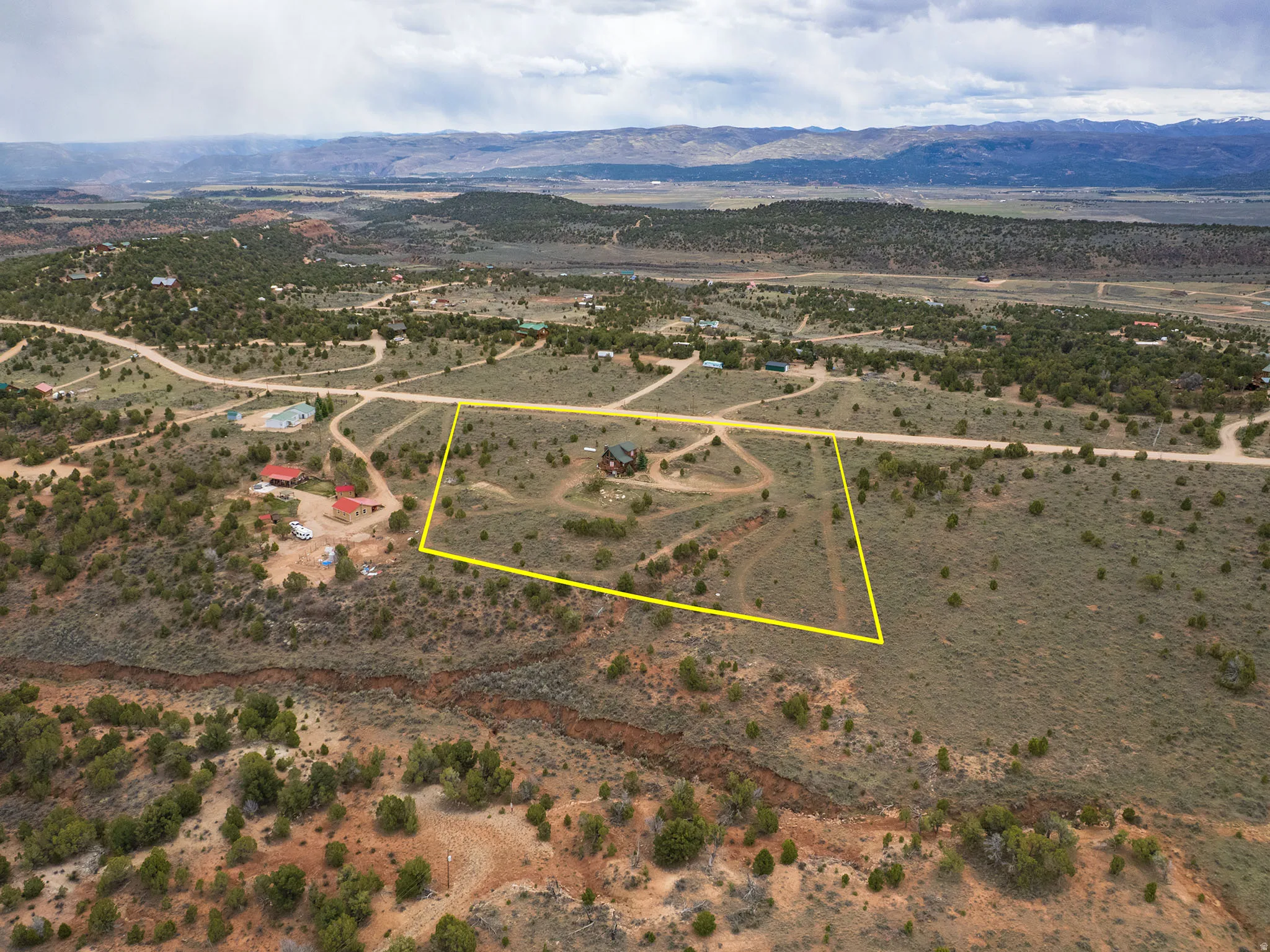 Aerial view of sparsely populated area with a mountain backdrop and property parcel outlined