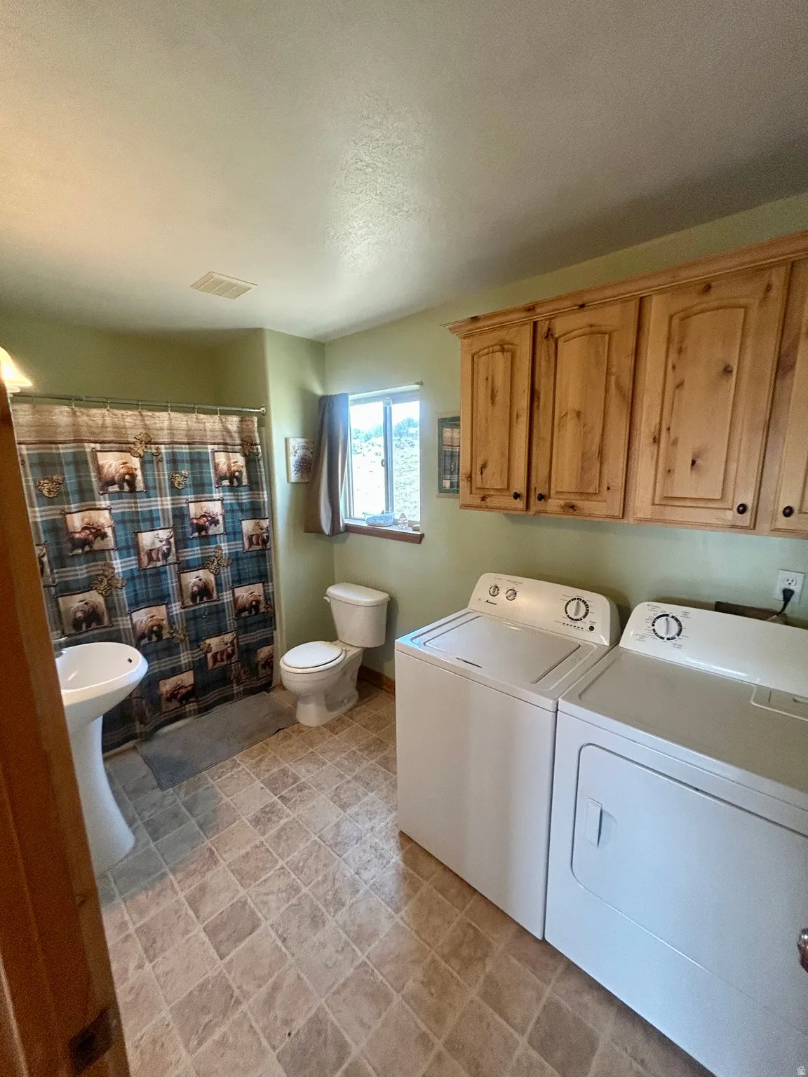 Bathroom featuring a pedestal sink, white toilet, and a window for natural light